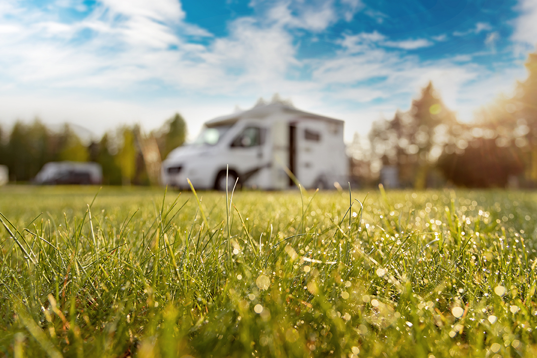 Family vacation travel RV, holiday trip in motorhome motorhome in campsite with grass in the foreground in focus. The Wobblebox, Sell Your Motorhome, UK